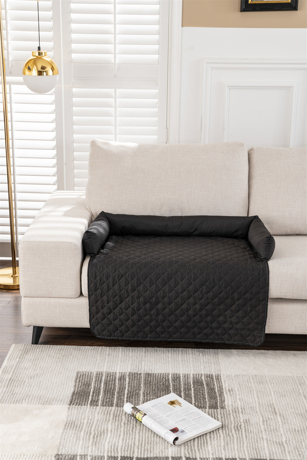 Black quilted sofa cover on a beige sofa in a living room setting.