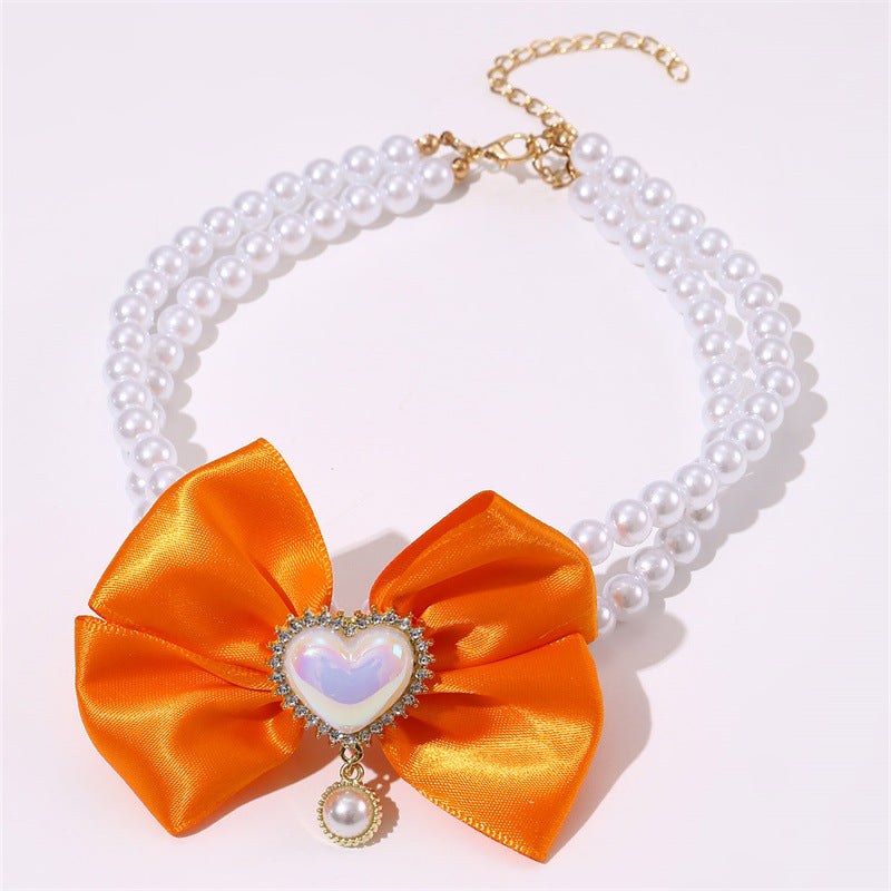 Necklace with an orange bow and heart-shaped pendant on a white background