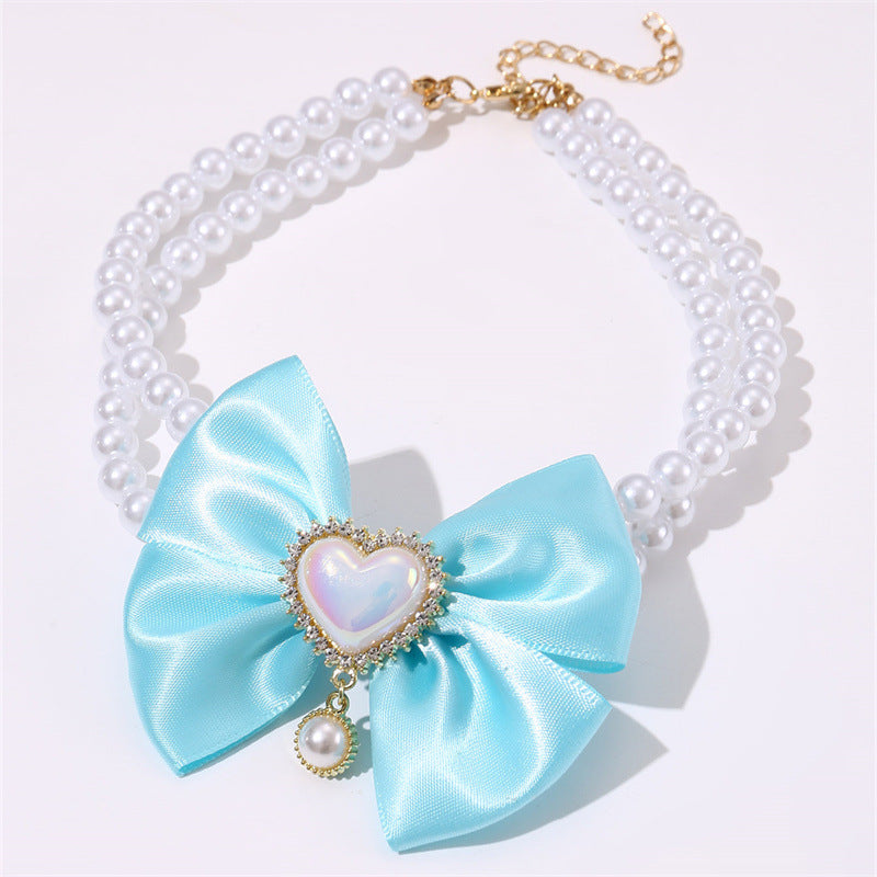 Necklace with a large blue bow and heart-shaped center on a white background