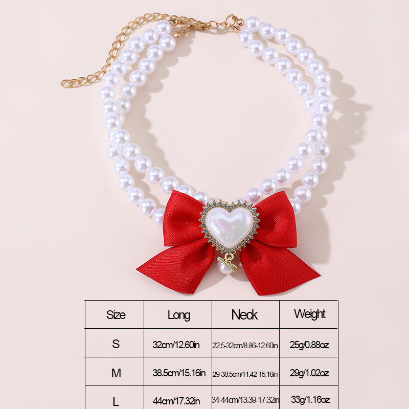 Pearl necklace with a red bow and heart-shaped center on a beige background
